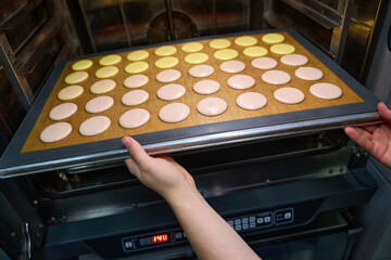 Experienced pastry chef is baking batch of biscuits in kitchen