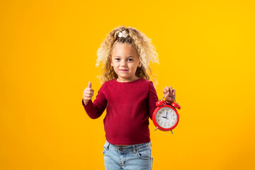 Young girl holding an alarm clock, symbolizing time management, education, school, and the urgency of deadlines and study.