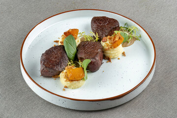 Small steaks garnished with greens. Some mashed potatoes. Macro, horizontal photo