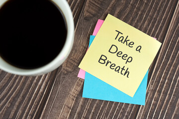 Take a deep breath text on adhesive note and cup of coffee
