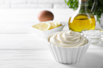 Fresh mayonnaise sauce in bowl on white wooden table, space for text