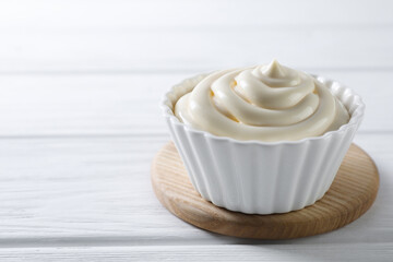 Fresh mayonnaise sauce in bowl on white wooden table, closeup. Space for text
