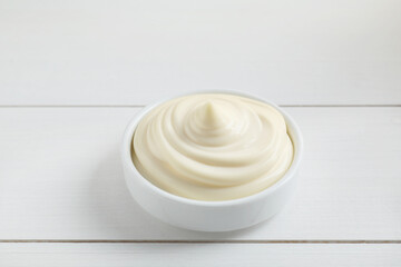 Fresh mayonnaise sauce in bowl on white wooden table