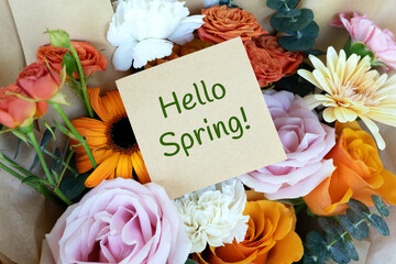 Hello Spring text on adhesive note and bunch of flowers bouquet