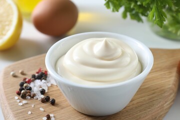 Tasty mayonnaise sauce in bowl and spices on table, closeup