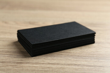 Blank black business cards on wooden table, closeup. Mockup for design