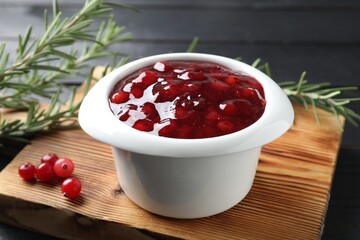 Cranberry sauce in bowl, fresh berries and rosemary on table, closeup