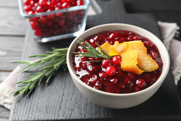 Fresh cranberry sauce, rosemary and orange peel in bowl on table, closeup