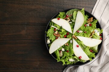 Delicious pear salad in bowl on wooden table, top view. Space for text