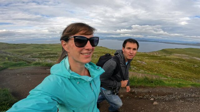 SELFIE: Happy tourist couple climbing the scenic path to the Old Man Of Storr. During an adventure holiday on picturesque Isle of Skye, they admire the beautiful natural scenery as they hike uphill.