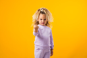 Child girl showing fist at camera. Negative emotions concept