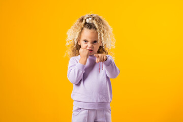 Child girl showing fist and pointing her finger at camera. Negative emotions concept
