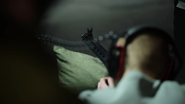 A man shooting a rifle in a shooting range. Shot from behind, Slow motion