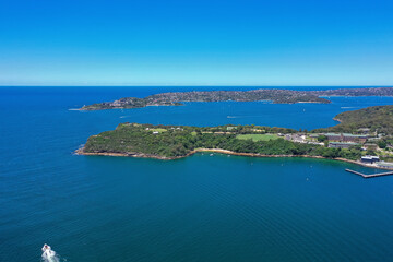 Naklejka na ściany i meble High angle aerial drone view of Cobblers Beach and Middle Head in the suburb of Mosman, Sydney, New South Wales, Australia. South Head and suburb Vaucluse in the background.