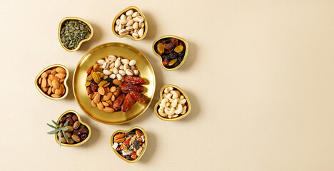 Mixed nuts and dried fruits on a gold plates. Symbols of the Jewish holiday of Tu Bishvat. Healthy snack - mix of organic nuts and dry fruits. - obrazy, fototapety, plakaty