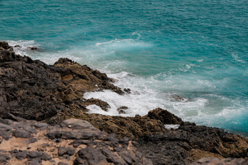 Ozean  türkis mit hellen weißen Schaumkronen spült an eine Steilklippe