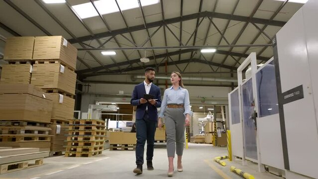 Female warehouse manager talking with logistics employee in warehouse, planning transport of products, goods, talking shipping process.