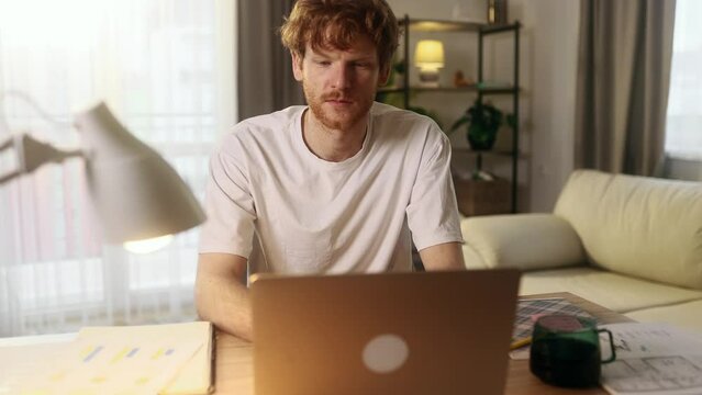 Handsome freelancer working on laptop checking email surfing web indoors Concentrated young man student having online distance education or work on computer and looking at screen at home workplace