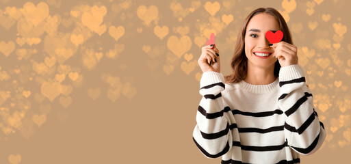 Beautiful young woman with red paper hearts on brown background with glowing lights. Valentines Day celebration