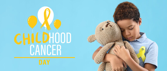 Little African-American boy with awareness ribbon and toy bear on light blue background. Banner for International Childhood Cancer Day