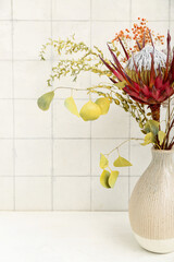 Vase with beautiful protea flower on table in room