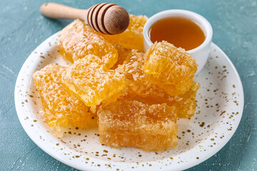 Plate with sweet honeycombs on blue background