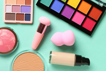 Composition with different cosmetic products and makeup sponges on color background