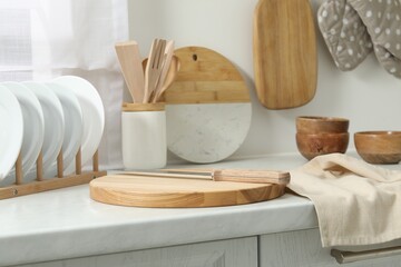 Wooden cutting boards, other cooking utensils and dishware on white countertop in kitchen