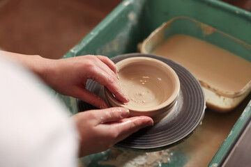 Clay crafting. Woman making bowl on potter's wheel, closeup