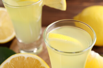Tasty limoncello liqueur with lemon on table, closeup. Space for text