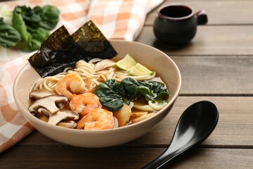 Delicious ramen with shrimps and mushrooms in bowl served on wooden table, closeup. Noodle soup