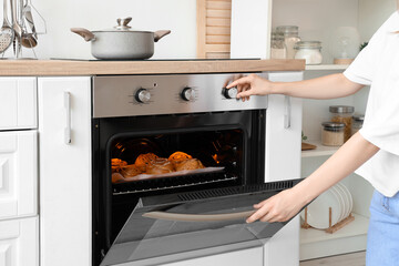 Woman opening oven with buns in kitchen