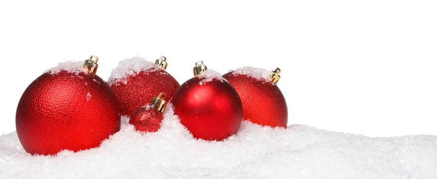 Beautiful red Christmas balls on snow against white background