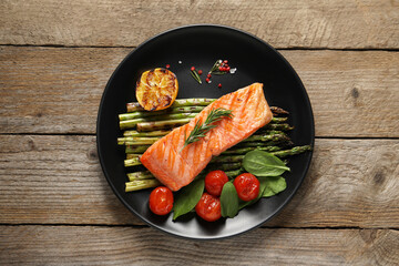 Tasty grilled salmon with tomatoes, asparagus and spices on wooden table, top view