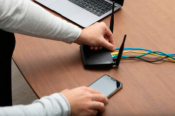Man with smartphone connecting to internet via Wi-Fi router at wooden table, closeup