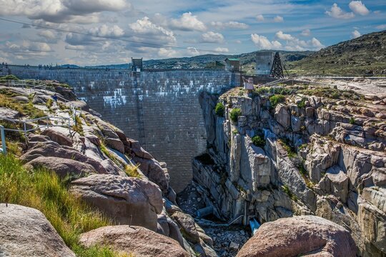 Alcova, Wyoming - 6/27/2018: Pathfinder dam, with water exiting the power house, constructed in 1909 of granite stone blocks,  near Alcova, Wyoming.