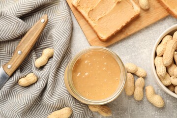 Tasty peanut butter sandwich and peanuts on gray table, flat lay