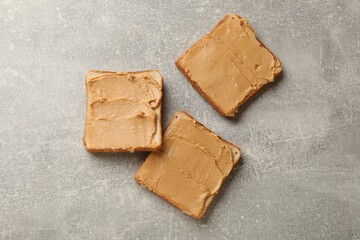 Tasty peanut butter sandwiches on gray table, flat lay