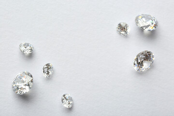 Many beautiful shiny diamonds on white background, flat lay. Space for text