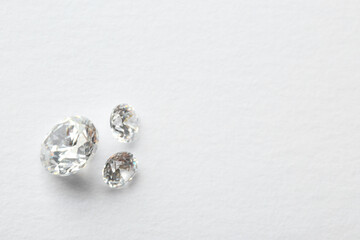 Beautiful shiny diamonds on white background, flat lay. Space for text