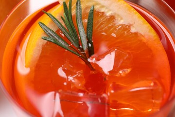 Aperol spritz cocktail, ice cubes, rosemary and orange slices in glass, closeup