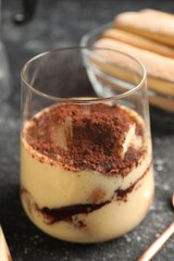 Delicious tiramisu in glass on grey table, closeup