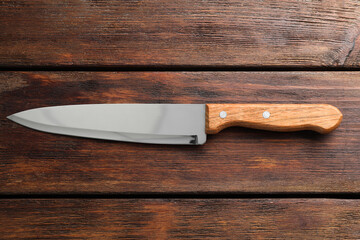 One sharp knife on wooden table, top view