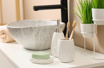 Different bath accessories and personal care products near sink on bathroom vanity
