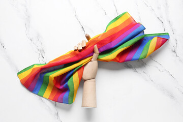 Wooden hand with rainbow fabric on grunge background. LGBTQ concept