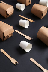 Takeaway paper cups, boxes and forks on black background