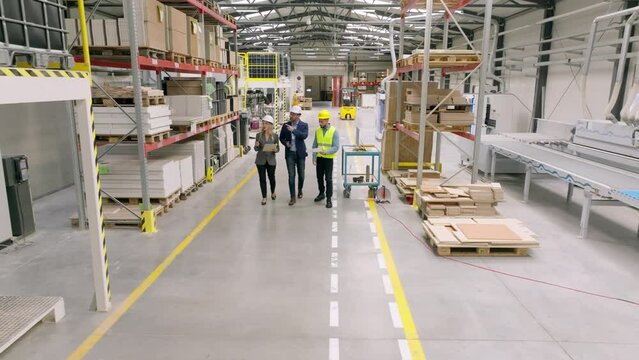 Top view of engineers consulting with director in modern industrial factory, talking about new production project or investment. Team management in manufacturing facility.