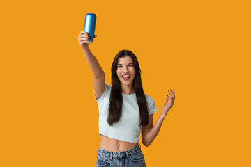 Beautiful young woman with can of cold beer on yellow background