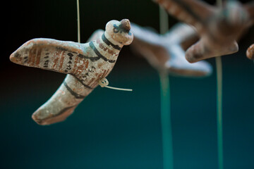 Birds made with clay and painted for a hanging by a potter in front of a lush green foliage