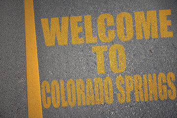 asphalt road with text welcome to colorado springs near yellow line.